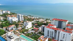 A coastal residential area with multiple buildings, a swimming pool, and a view of the sea. - Maralma 903: Panoramic Views and Rooftop Pool (Bucerías)