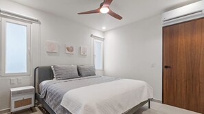 A bedroom with a bed, a ceiling fan, and a wooden wardrobe. - Maralma 903: Panoramic Views and Rooftop Pool (Bucerías)