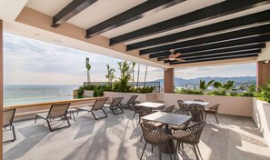 Une terrasse avec des sièges extérieurs, une vue sur l’océan et un paysage urbain en arrière-plan.