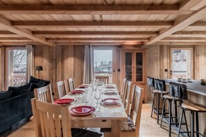 Enjoy meals in this cozy dining area with a long table, black sofa, and bar area.