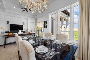A dining area with a table set for four, a chandelier, and a view of the outdoors.