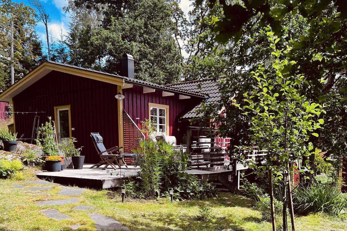 Una casa in legno rossa con veranda, posti a sedere all'aperto e piante in vaso.