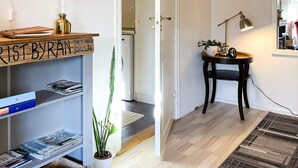 Un couloir avec un panneau en bois, une plante en pot, un bureau avec une lampe et un tapis.