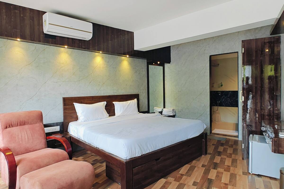 Une chambre à coucher comprenant un lit, une chaise, une coiffeuse avec un miroir et un appareil de climatisation.
