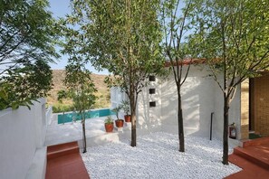 A courtyard with white walls, a pool, and potted plants. - The High Garden Resort (Udaipur)