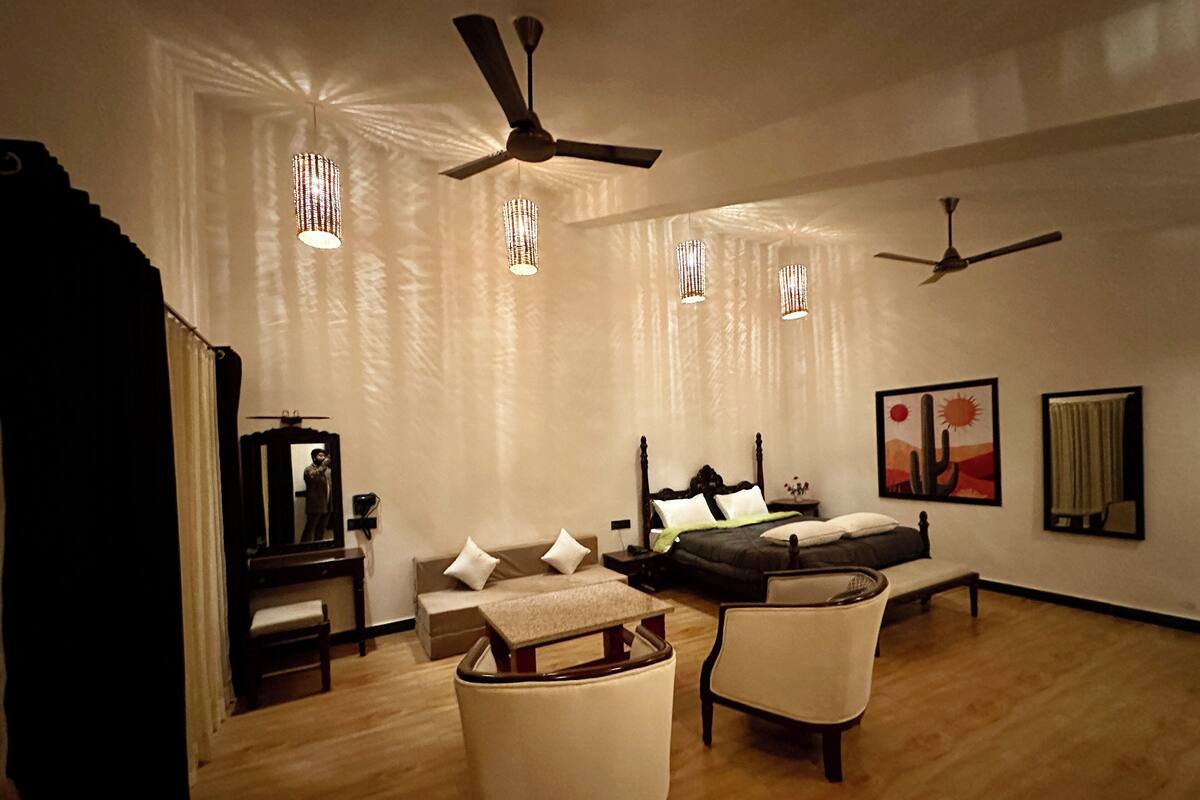 Une chambre moderne avec un lit, deux chaises, un bureau et un ventilateur de plafond.