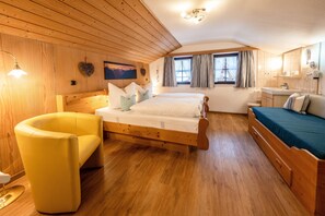 Une pièce aux murs lambrissés, comprenant un lit, une chaise, une fenêtre et une salle de bain.