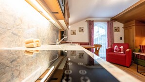 Una cocina moderna con encimera de mármol, estufa empotrada y un sofá rojo en la zona de estar.