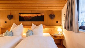 Un dormitorio tipo cabaña de madera con dos camas, una mesita de noche con lámpara y un cuadro en la pared.