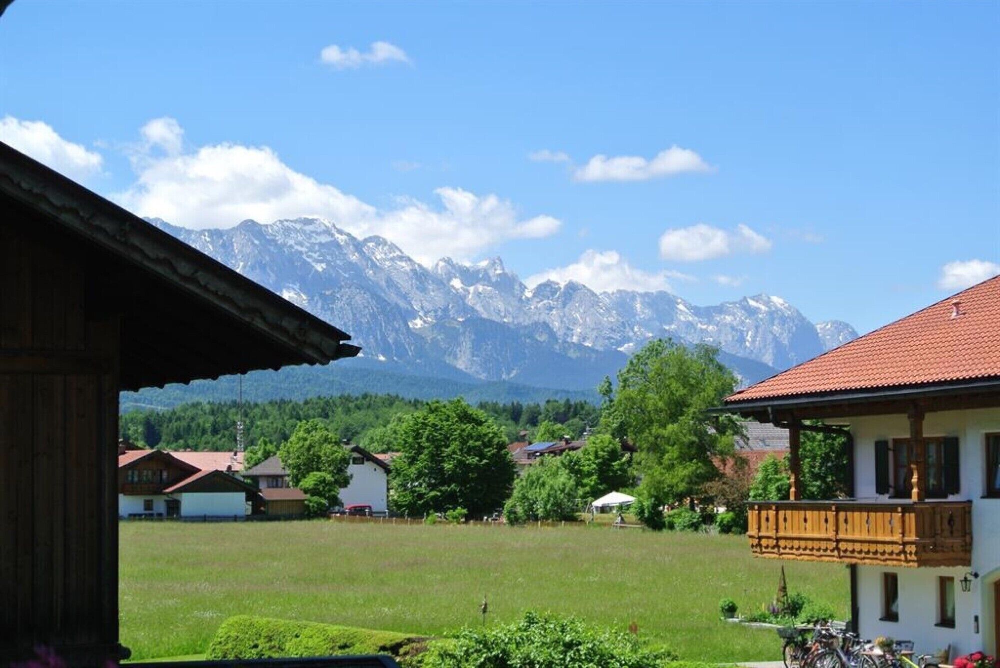 Bergblick mit einem Holzbauten und einem weißen Haus mit Balkon.