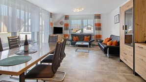 A modern living room with a dining area, a sofa set, and a TV.