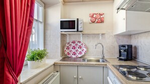 A compact kitchen with a microwave, a coffee machine, a sink, and a stove. - Fewo Alte Post, Apartment Rosenrot – Cozy Family Retreat in Meßstetten (Meßstetten)