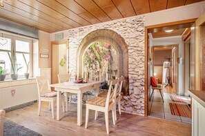 A dining area with a stone archway, wooden ceiling, and a view into another room. - Fewo Alte Post, Apartment Rosenrot – Cozy Family Retreat in Meßstetten (Meßstetten)