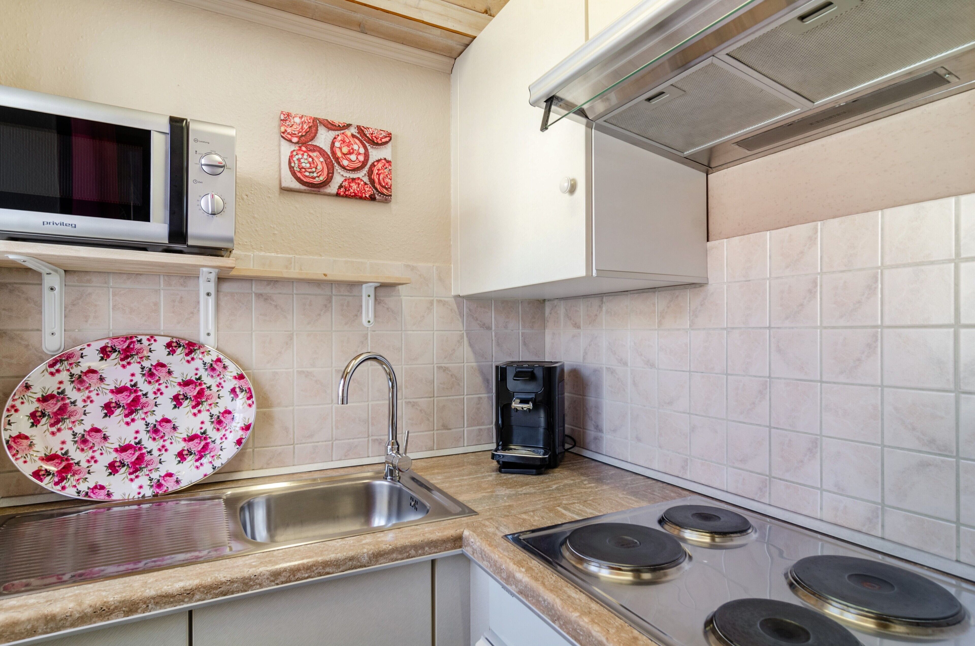 A kitchen with a microwave, coffee maker, sink, and stove.