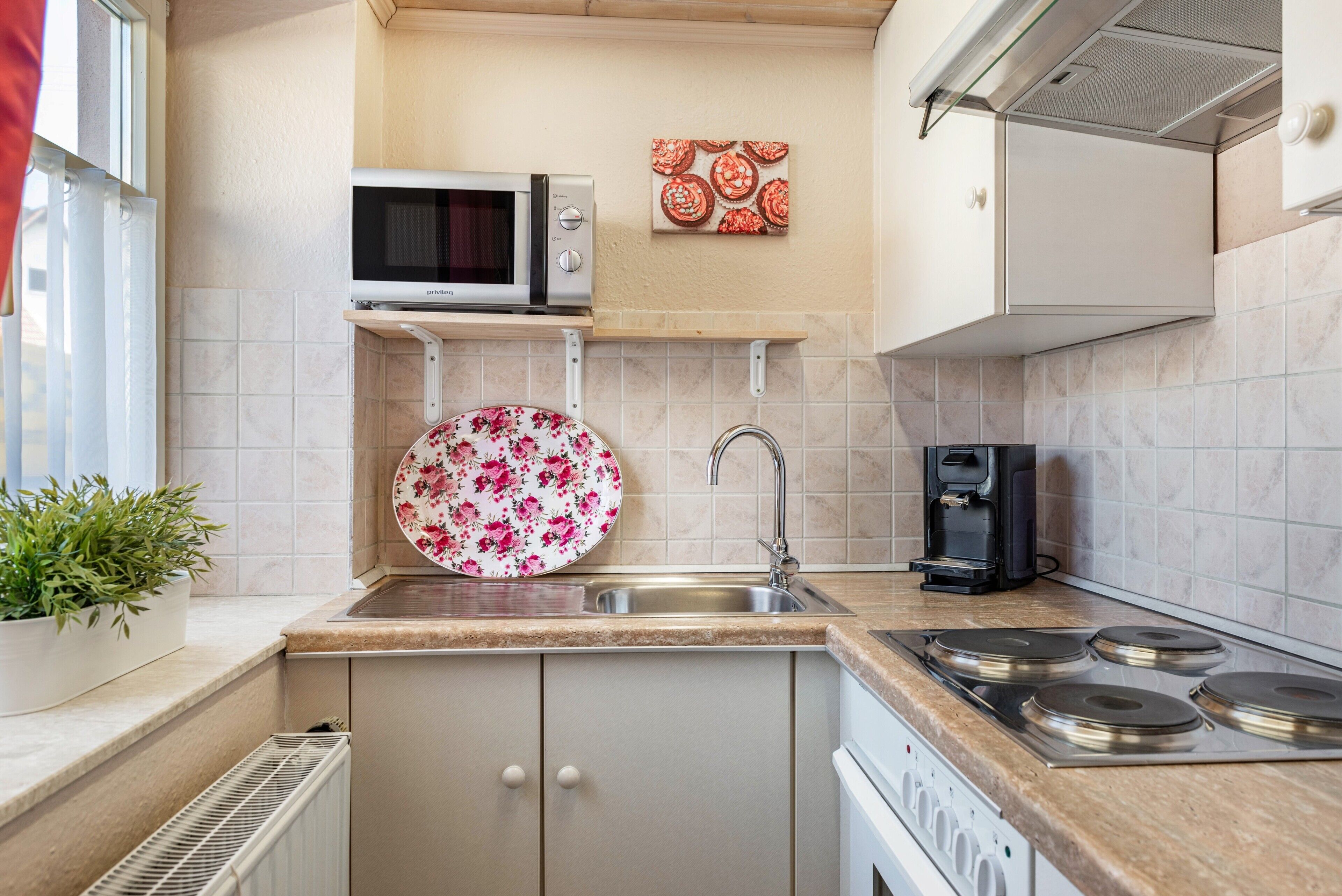 A kitchen with a microwave, coffee maker, sink, and stove.