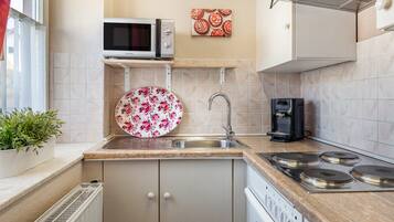 A kitchen with a microwave, coffee maker, sink, and stove.