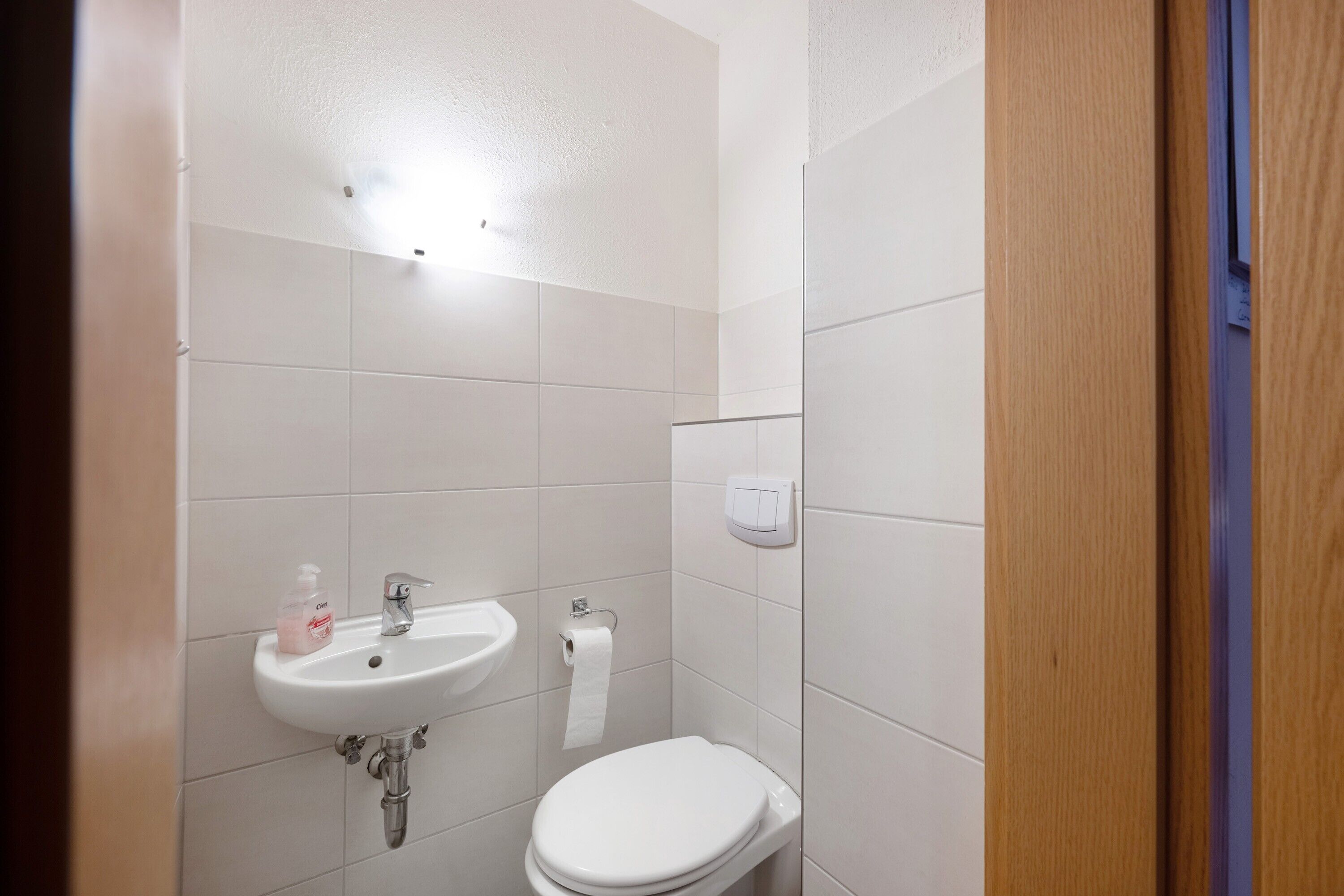 A bathroom with a white sink, toilet, and a hand dryer.