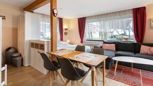 A modern room with a wooden ceiling, a dining table with chairs, a sofa, a bed, and a window with curtains. - Apartment 'Deichblick 3' with Shared Garden and Balcony (Hedwigenkoog)