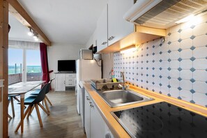 Una cocina compacta con cubierta de madera, un lavamanos y un salpicadero azulejado.