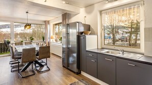 Een moderne keuken met een eethoek, grote ramen en uitzicht.
