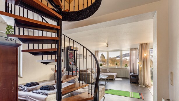 Een modern interieur met een spiltrap, een bank, een bijzettafeltje en uitzicht op de omgeving.