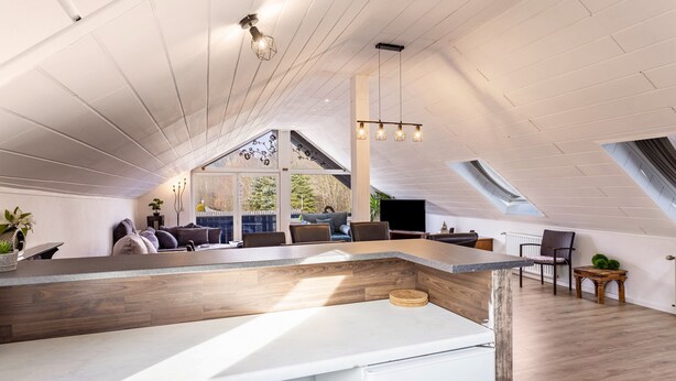 Moderni loft-tyylinen asunto, jossa on keittiösaareke, oleskelualue ja suuret ikkunat.