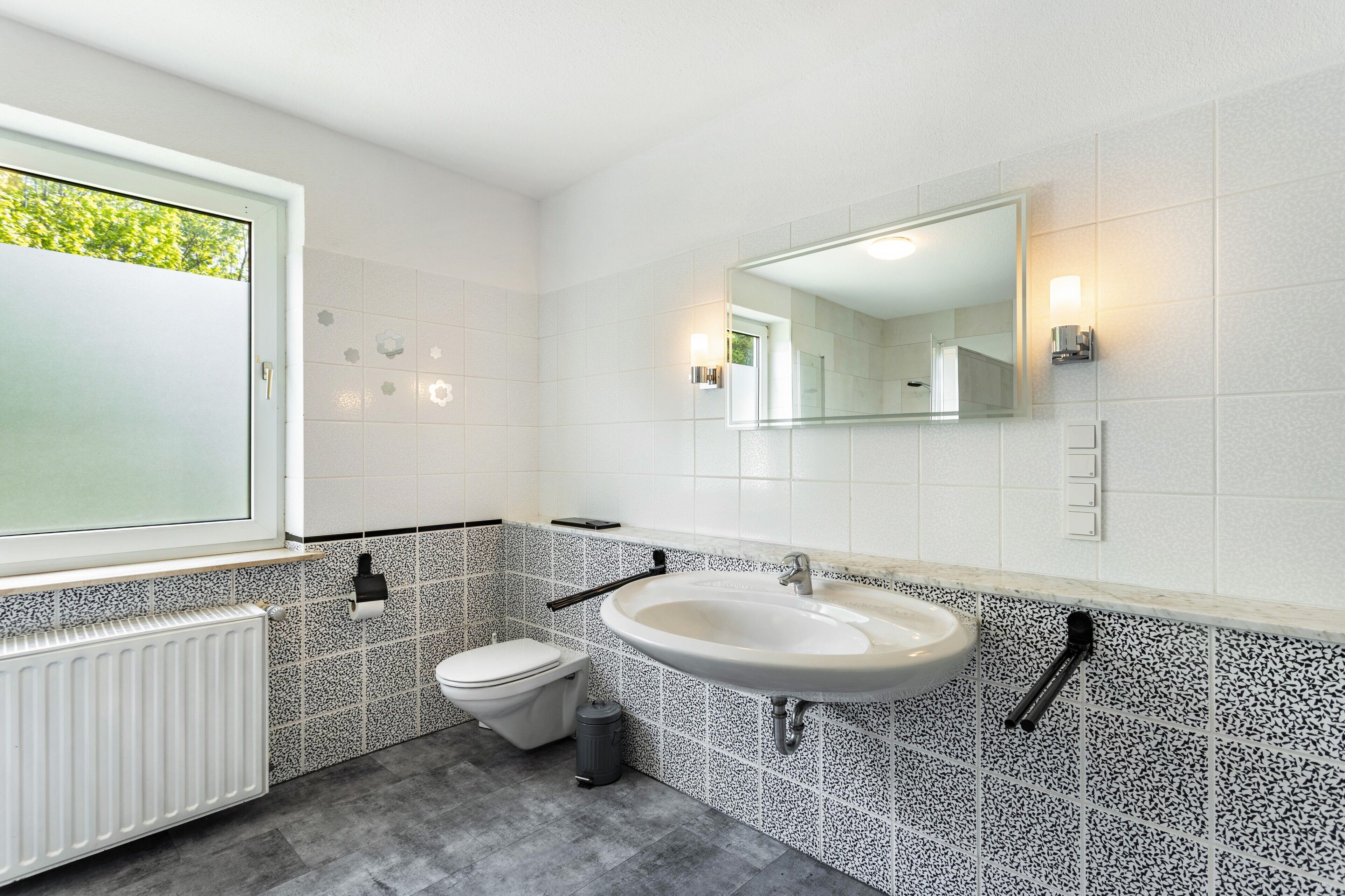 Un baño moderno con inodoro, lavamanos y espejo.