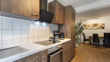 Een moderne keuken met houten kastjes, een inbouwoven en een koffiezetapparaat.
