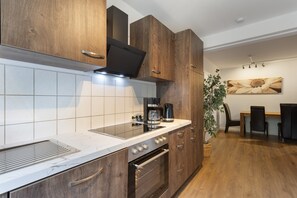 A modern kitchen with wooden cabinets, a built-in oven, and a coffee maker.