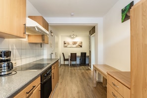 A modern kitchen with wooden cabinets, a built-in oven, and a coffee maker.