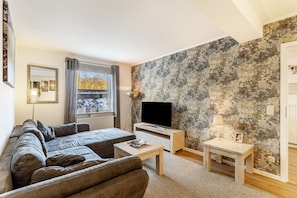 A living room with a sofa, TV, and a wall with a textured pattern.