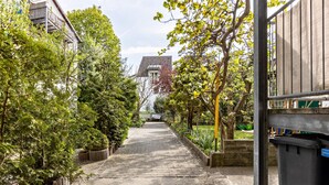 A pathway flanked by trees and buildings, leading to a distant structure.