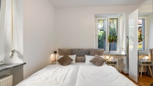 A bedroom with a bed, bedside tables, a window with a view, and a radiator.