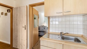 A compact kitchen with wooden cabinets, a stainless steel sink, and a tiled backsplash. - Apartment 'Piste 4' with Shared Terrace, Balcony and Wi-Fi (Willingen (Upland))