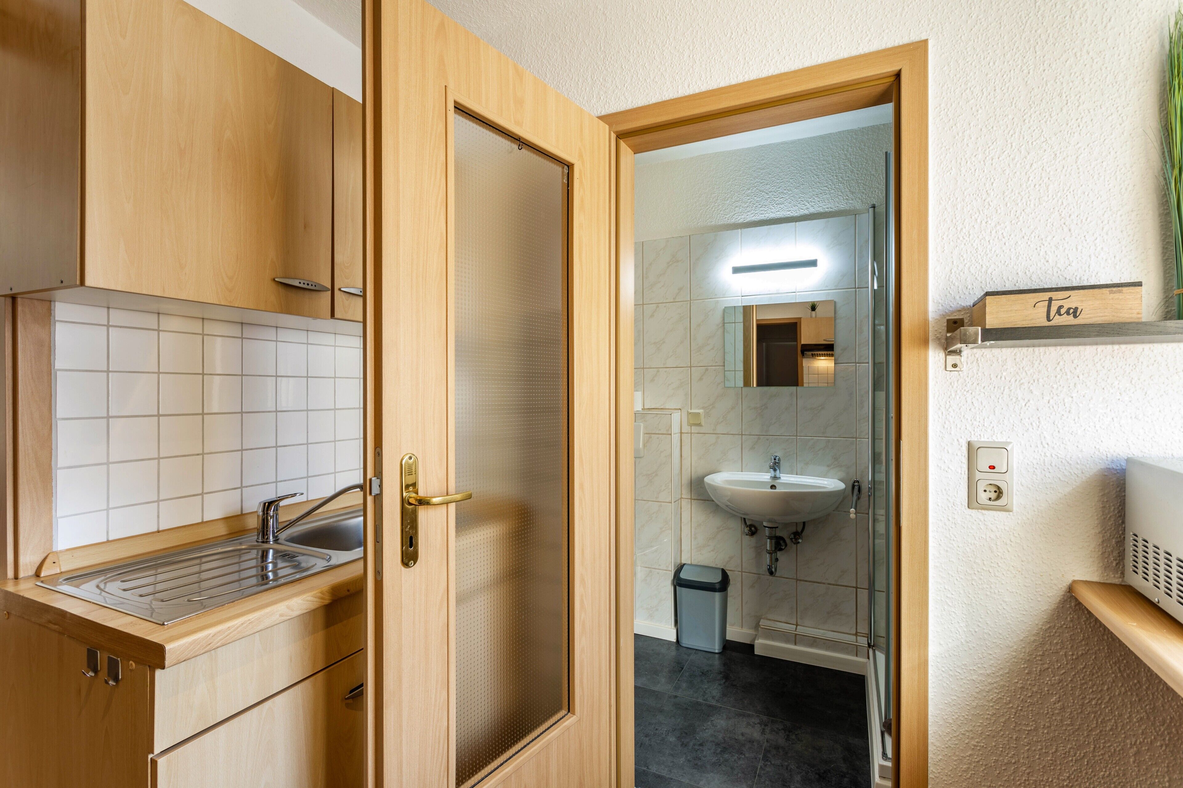 Un baño moderno con un mueble de tocador de madera, un lavamanos y un espejo.