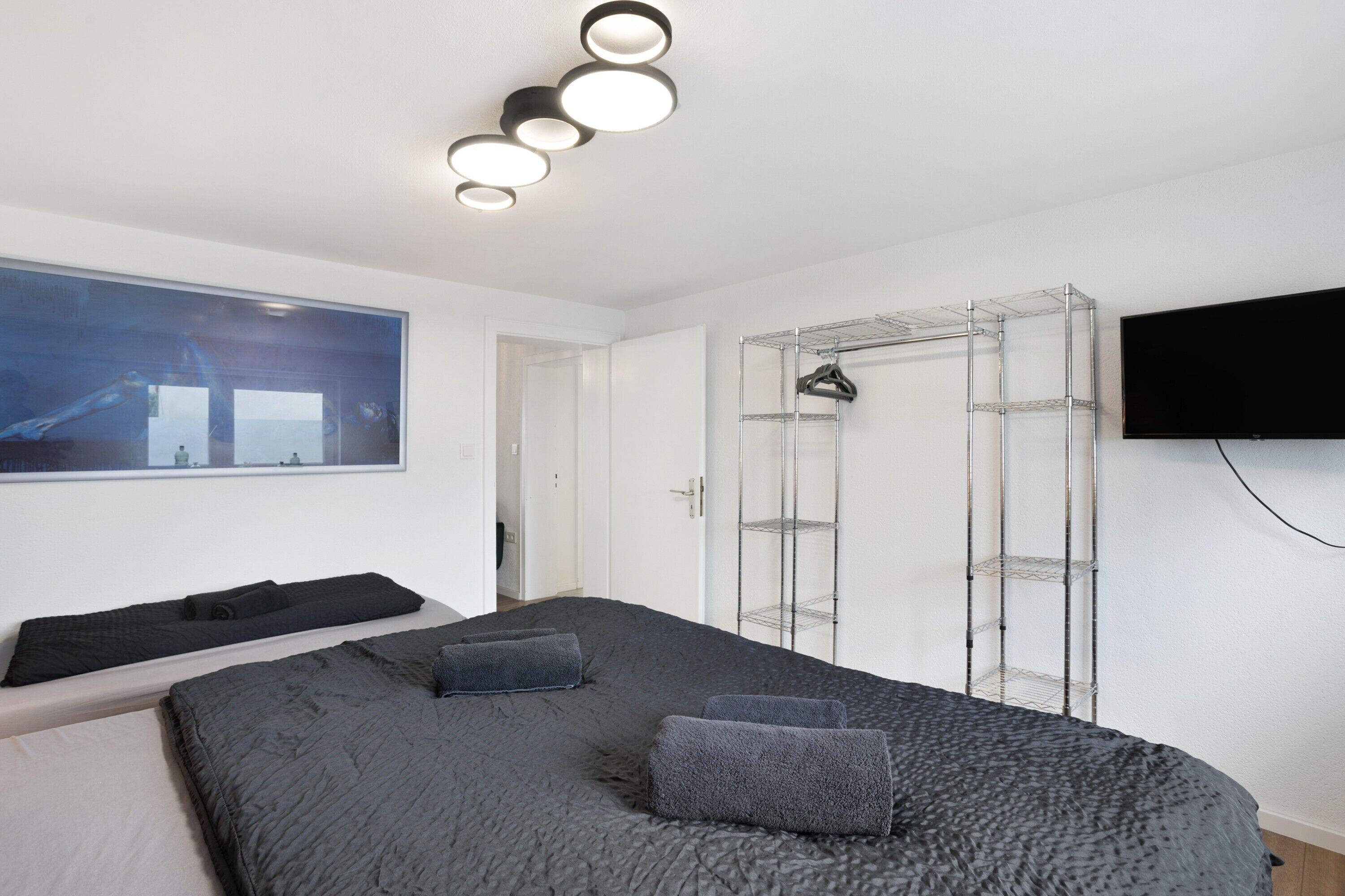 Una camera da letto con un letto, una TV, un armadio e un quadro appeso al muro.