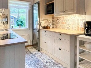 A kitchen with a tiled backsplash, a built-in microwave, and a coffee maker on the counter. - 5 Person Holiday Home in Farjestaden (Farjestaden)