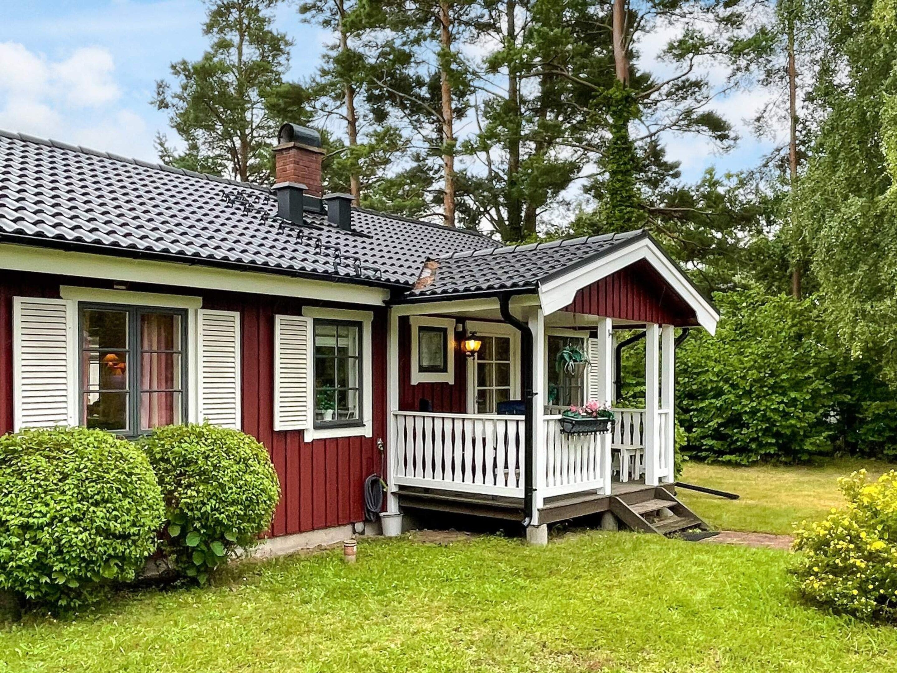 A red house with a white porch and a chimney.