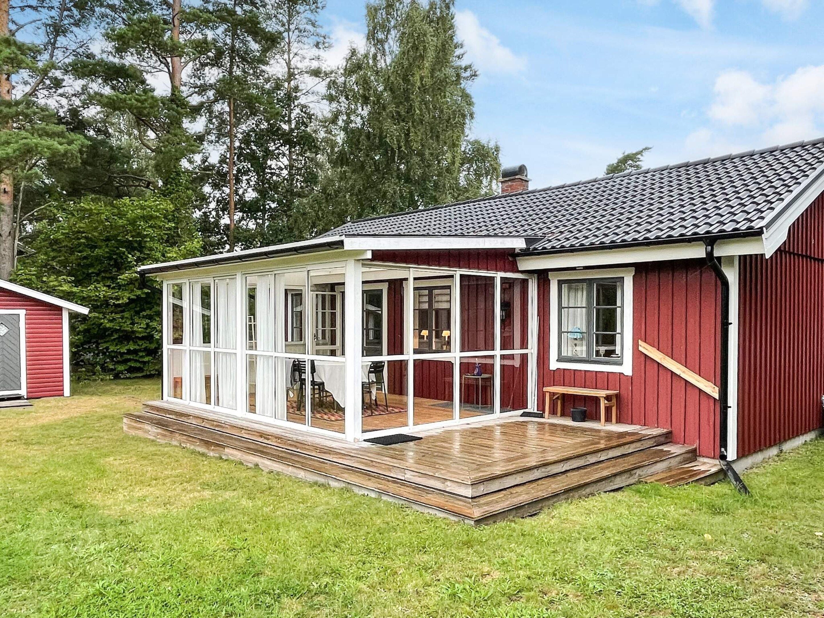 A red wooden house with a covered porch and a small deck.