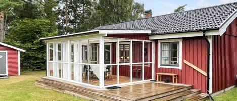A red wooden house with a covered porch and a small deck.