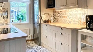Eine moderne Küche mit einem großen Fenster, einem Kühlschrank, einer Mikrowelle und einer Kaffeemaschine auf der Arbeitsplatte.