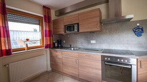 Eine moderne Küche mit Holzausbau, einer Mikrowelle, einem Herd und einem Fenster mit Vorhängen.