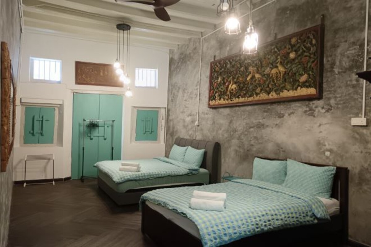 A hotel room with two beds, a ceiling fan, and a large painting on the wall.