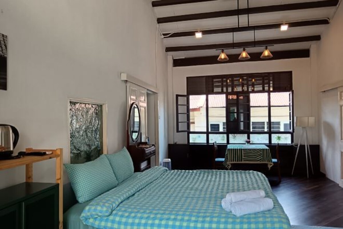 A bedroom with a bed, a desk, and a window.