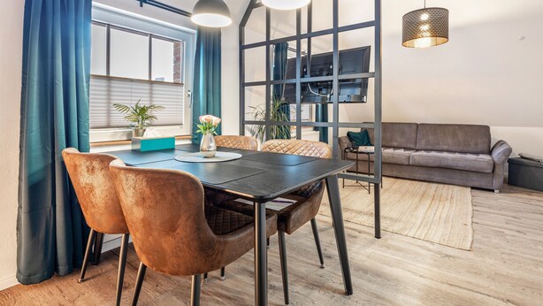 A modern dining area with a table, chairs, and pendant lights. - Apartment “Cosy in Soltau” with Private Terrace, Wi-Fi, and Air Conditioning (Soltau)