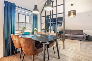 A modern dining area with a table, chairs, and pendant lights. - Apartment “Cosy in Soltau” with Private Terrace, Wi-Fi, and Air Conditioning (Soltau)
