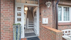 A brick house entrance with a white door, a staircase, and a mailbox. - Apartment “Cosy in Soltau” with Private Terrace, Wi-Fi, and Air Conditioning (Soltau)