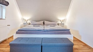 A bedroom with a bed, bedside lamps, a window, and a radiator. - Apartment “Cosy in Soltau” with Private Terrace, Wi-Fi, and Air Conditioning (Soltau)