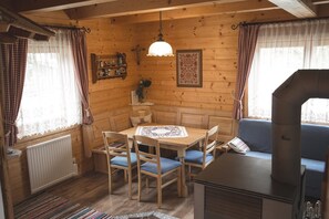 A cozy cabin interior with a wooden dining table, blue cushioned chairs, a bench, a hanging light fixture, and a rustic stove. - Holiday Home 'Klippitzblick' with Private Terrace and Private Garden (Bad St. Leonhard)