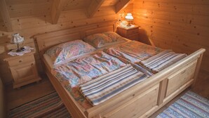 Un dormitorio de cabaña de madera con cama, mesita de noche y lámpara.